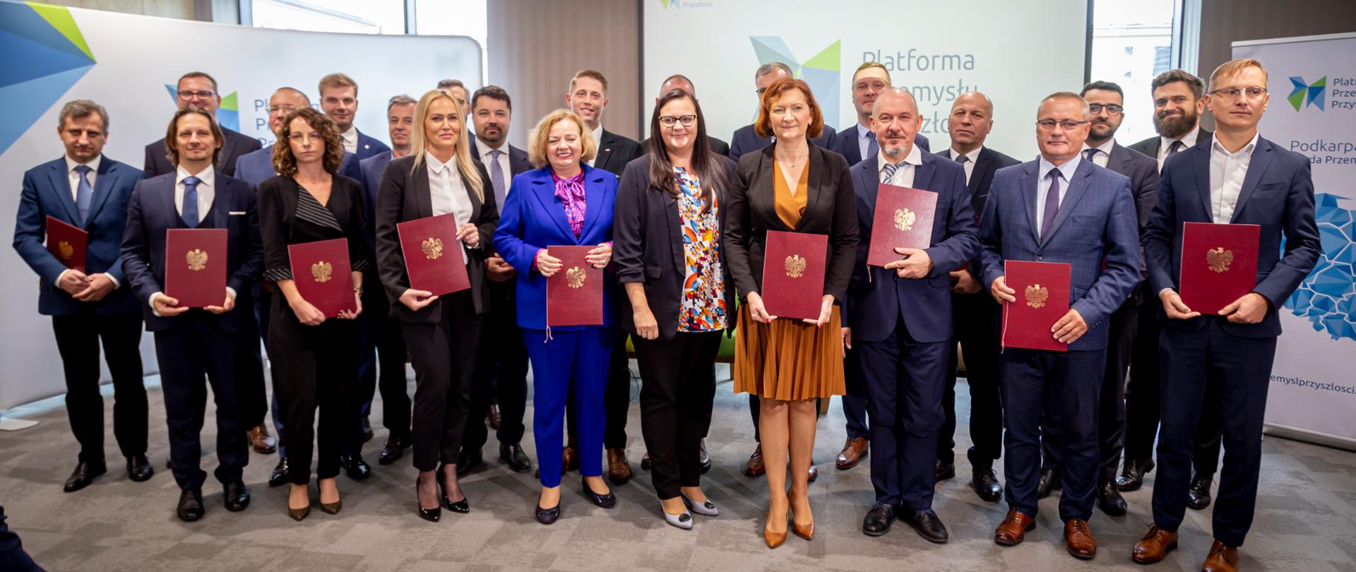 Grupa osób w sali pozuje do zdjęcia. W środku wiceminister Małgorzata Jarosińska-Jedynak.