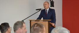W świetlicy komendy powiatowej PSP w Rawiczu trwa narada podsumowująca rok 2023. Przy mównicy stoi starosta rawicki, który składa strażakom podziękowania za służbę w minionym roku. 