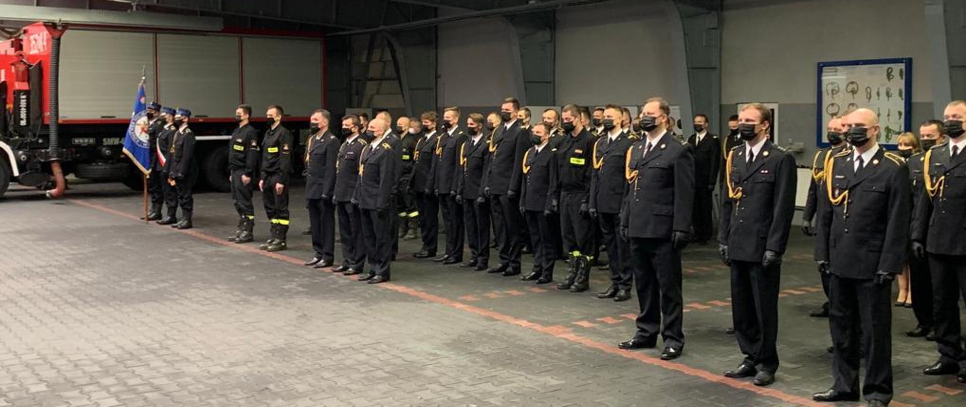 Na zdjęciu funkcjonariusze Państwowej Straży Pożarnej podczas uroczystego apelu. Funkcjonariusze w umundurowaniu galowym. 