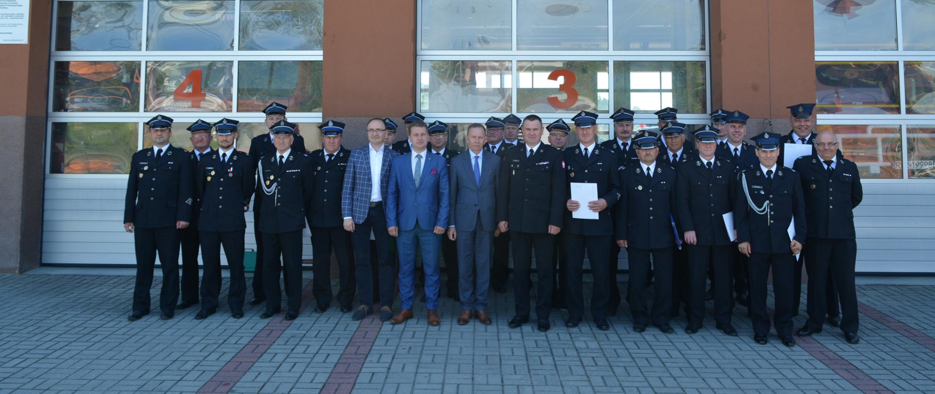 Na zdjęciu prezesi jednostek OSP z Terenu Powiatu Strzyżowskiego po podpisaniu umów na dofinasowanie. W tle bramy garażowe JRG w Strzyżowie