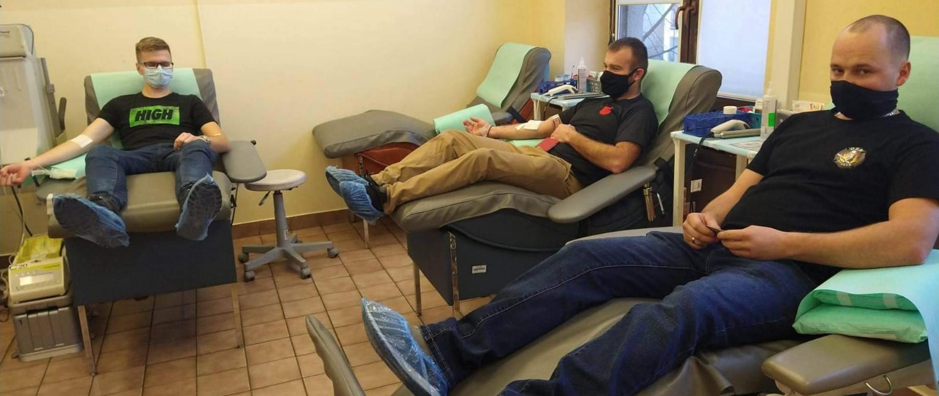 Trzech strażaków siedzi na fotelach i czeka na oddawanie krwi.
