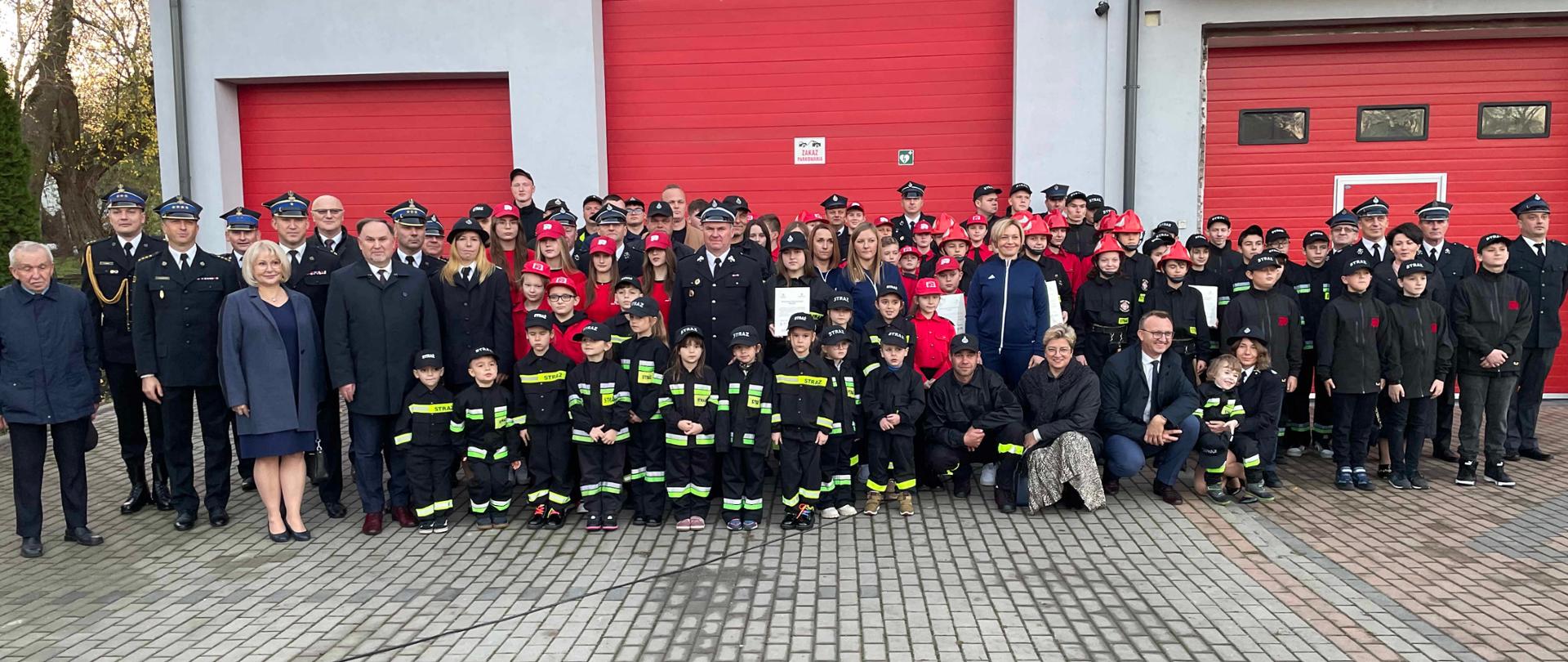 Zdjęcie przedstawia wszystkich uczestników uroczystości na tle remizy OSP Skotniki