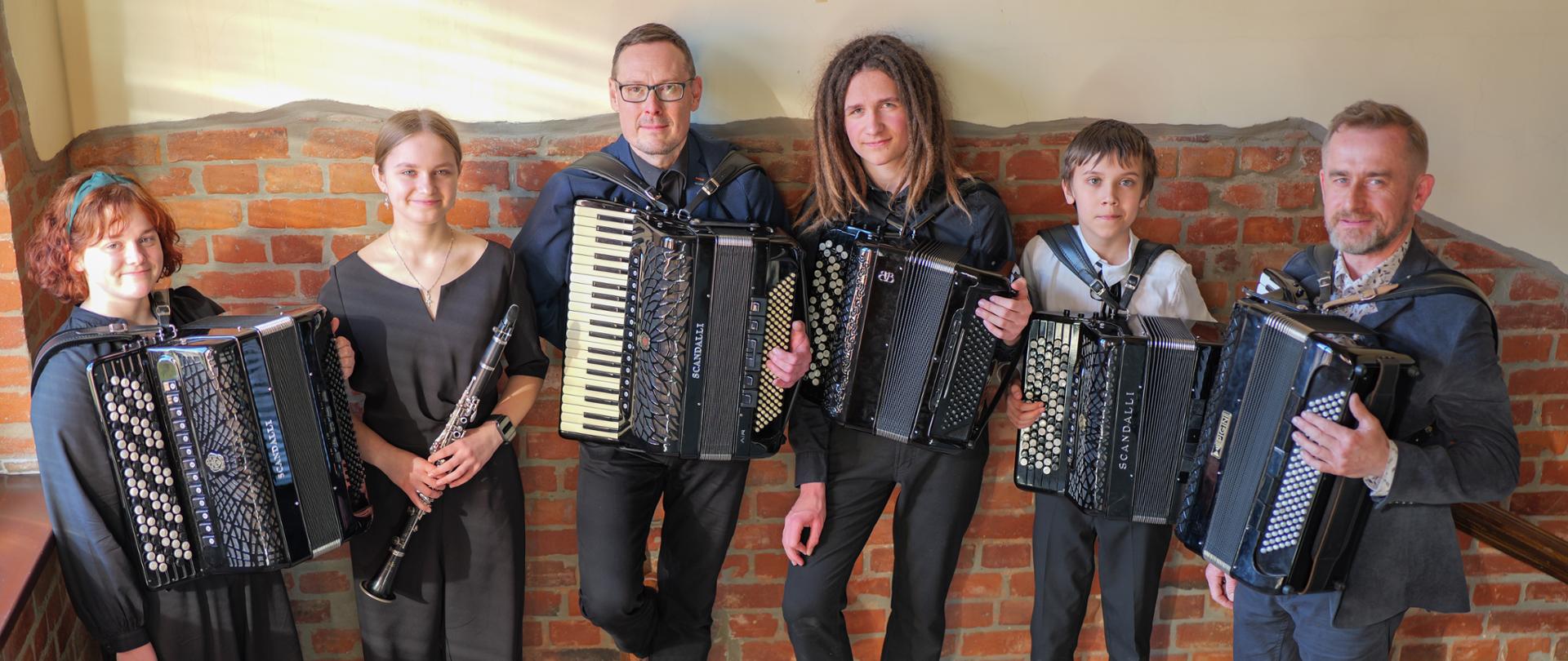 Andrzej Formelam Ryszard Borysionek wraz z grupą uczniów pozują na tle ceklanej ściany po koncercie w wejherowskim "elektryku".