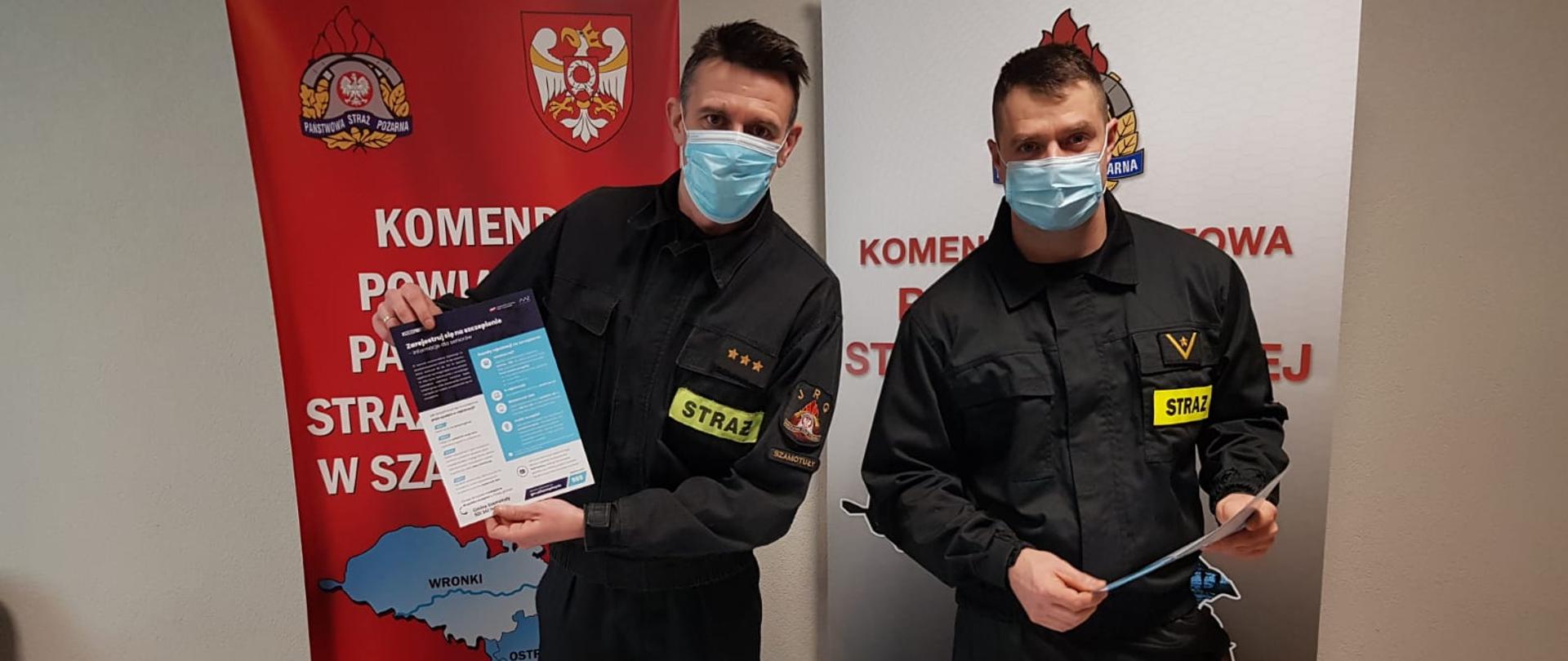 Dwóch umundurowanych strażaków prezentujących ulotki z akcji szczepień przeciwko COVID-19