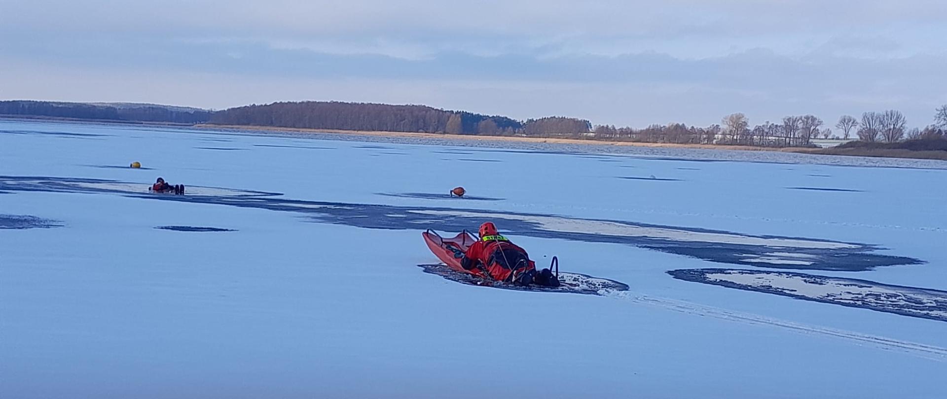 Strażak na saniach lodowych zbliża się do pozoranta, który jest w przeręblu