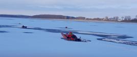 Strażak na saniach lodowych bliża się do pozoranta, który jest w przeręblu