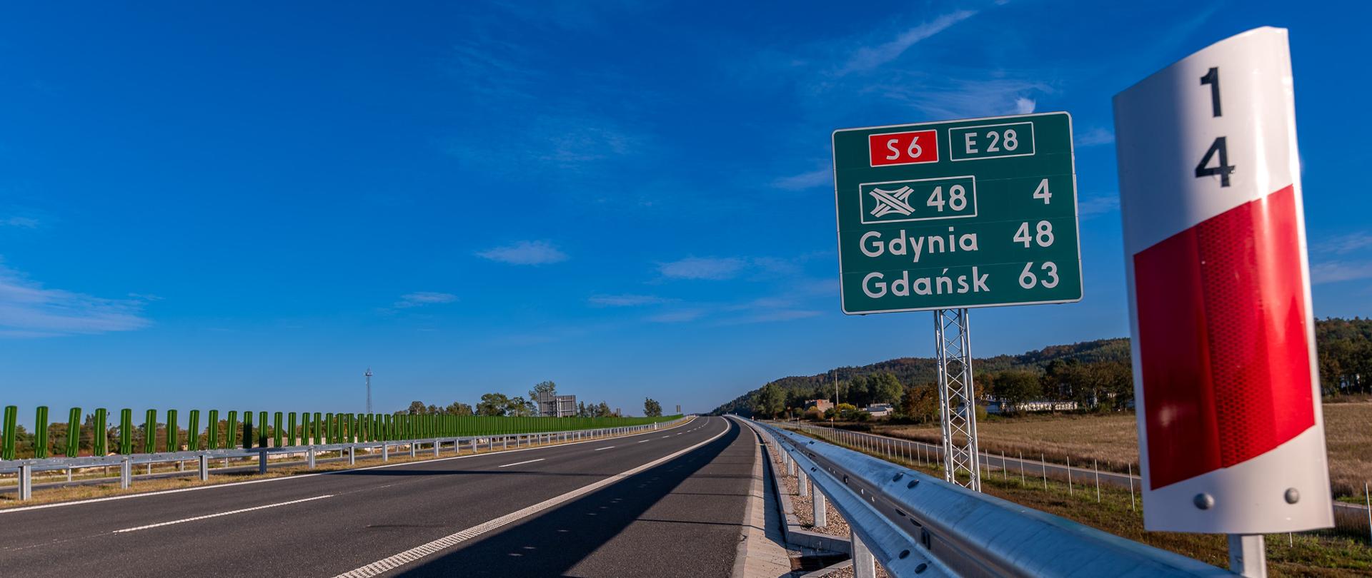 Odcinek drogi ekspresowej, widok z poziomu jezdni. Na pierwszym planie widoczny słupek pikietażowy, a za nim znak z informacją o liczbie kilometrów do Gdyni i Gdańska.