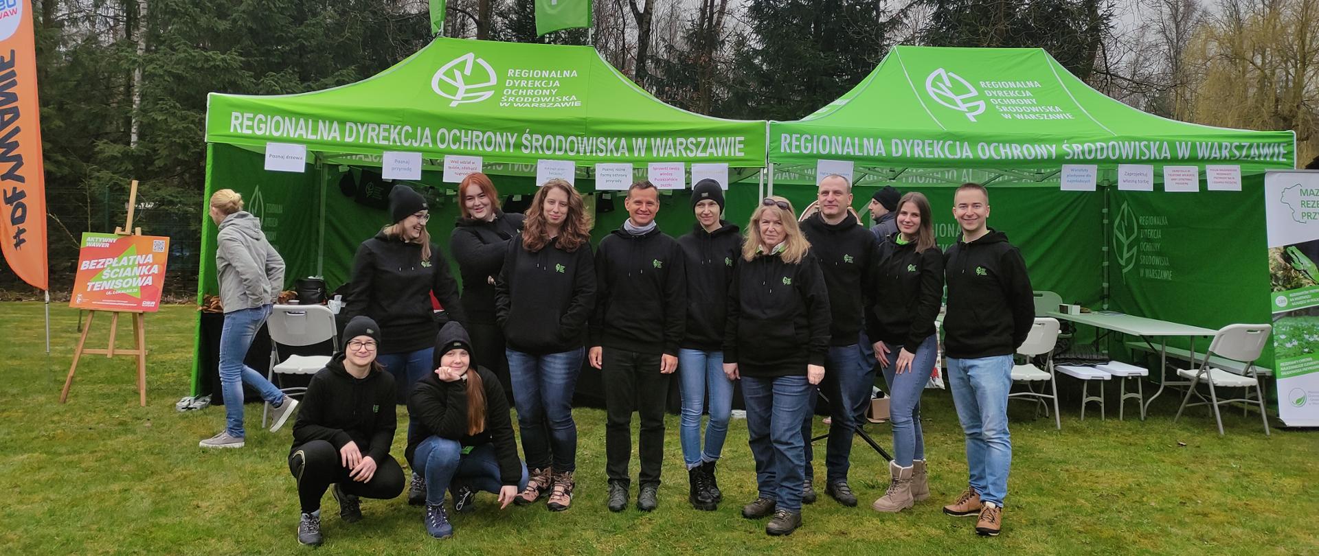 Grupa osób przed namiotami 