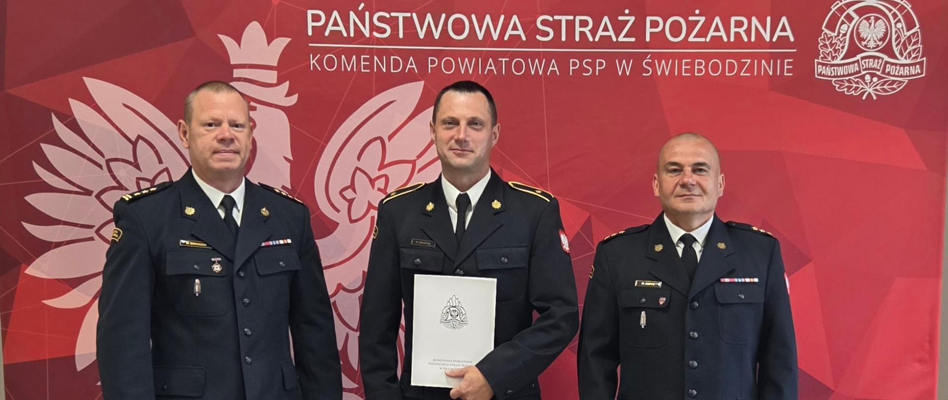 Zdjęcie przedstawia składanie gratulacji przez Zastępcę Komendanta Powiatowego starszego brygadiera Marcina Bohuszko oraz Zastępcy Naczelnika Wydziału Operacyjno-Kontrolno-Rozpoznawczego kapitana Krystiana Hoppe aspirantowi Mateuszowi Siekierskiemu z okazji jubileuszu 20 lat pracy zawodowej.