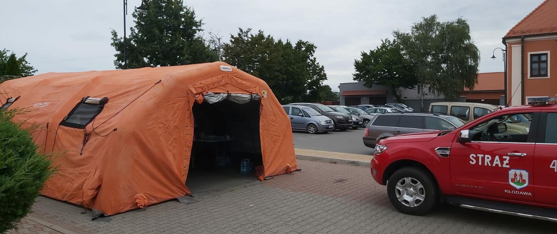 Zdjęcie przedstawia namiot, w którym zorganizowany został punkt szczepień. Obok znajduje się SLRR z OSP Kłodawa.