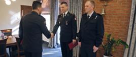 Komendant Centralnej Szkoły gratuluje otrzymanej nagrody jednemu z funkcjonariuszy, obok stojący drugi z nagrodzonych strażaków