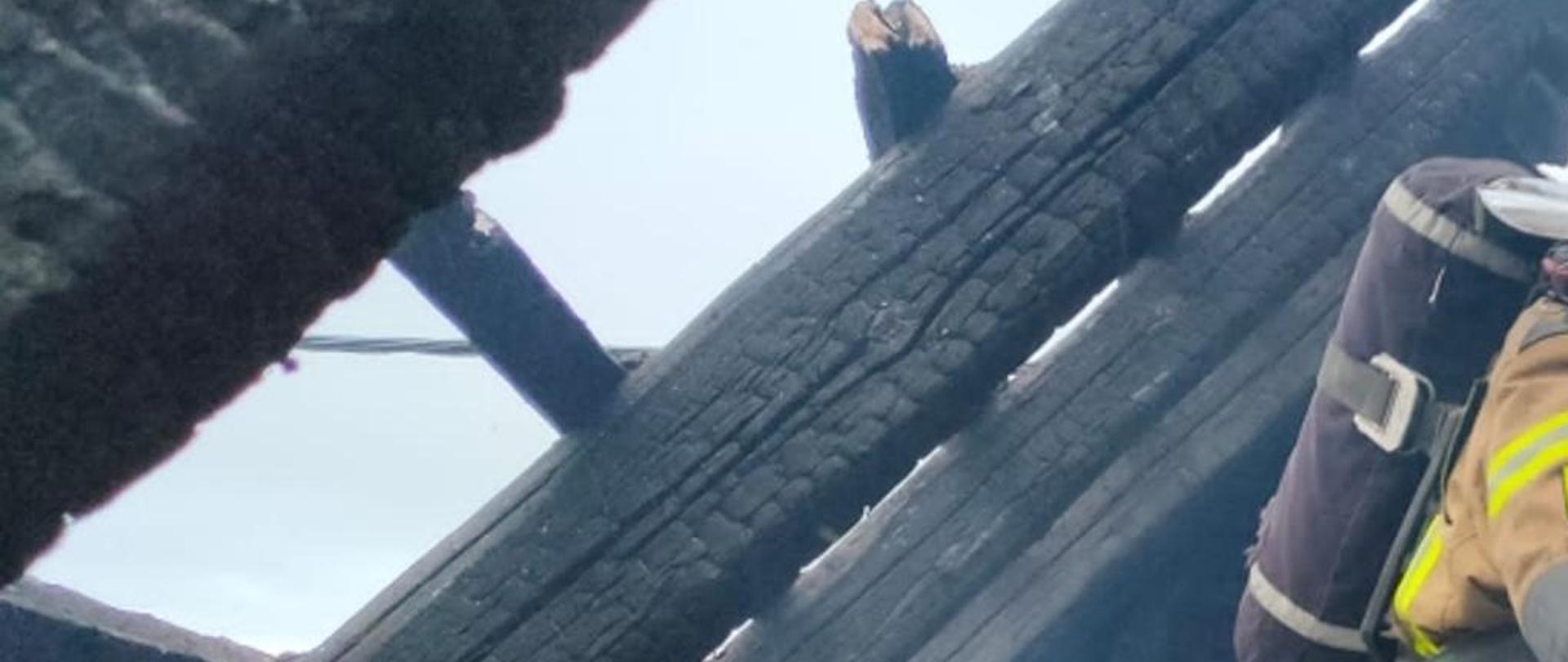 Zdjęcie przedstawia strażaka prowadzącego czynności rozbiórkowe konstrukcji dachowej budynku mieszkalnego podczas pożaru w miejscowości Chełmsko.