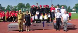 Powiatowe Zawody Sportowo - Pożarnicze MDP OSP, wg regulaminu CTiF 2023 - zwycięska drużyna stoi na podeście z pucharem i nagrodami, obok stoją osoby wręczające