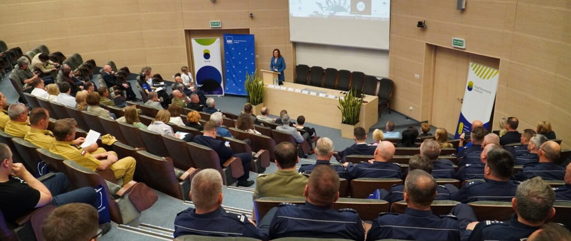 Uczestnicy konferencji dotyczącej uchodźców z Ukrainy w Polsce zgromadzeni w auli Uniwersytetu Rzeszowskiego słuchają przemówienia wojewody podkarpackiego Ewy Leniart