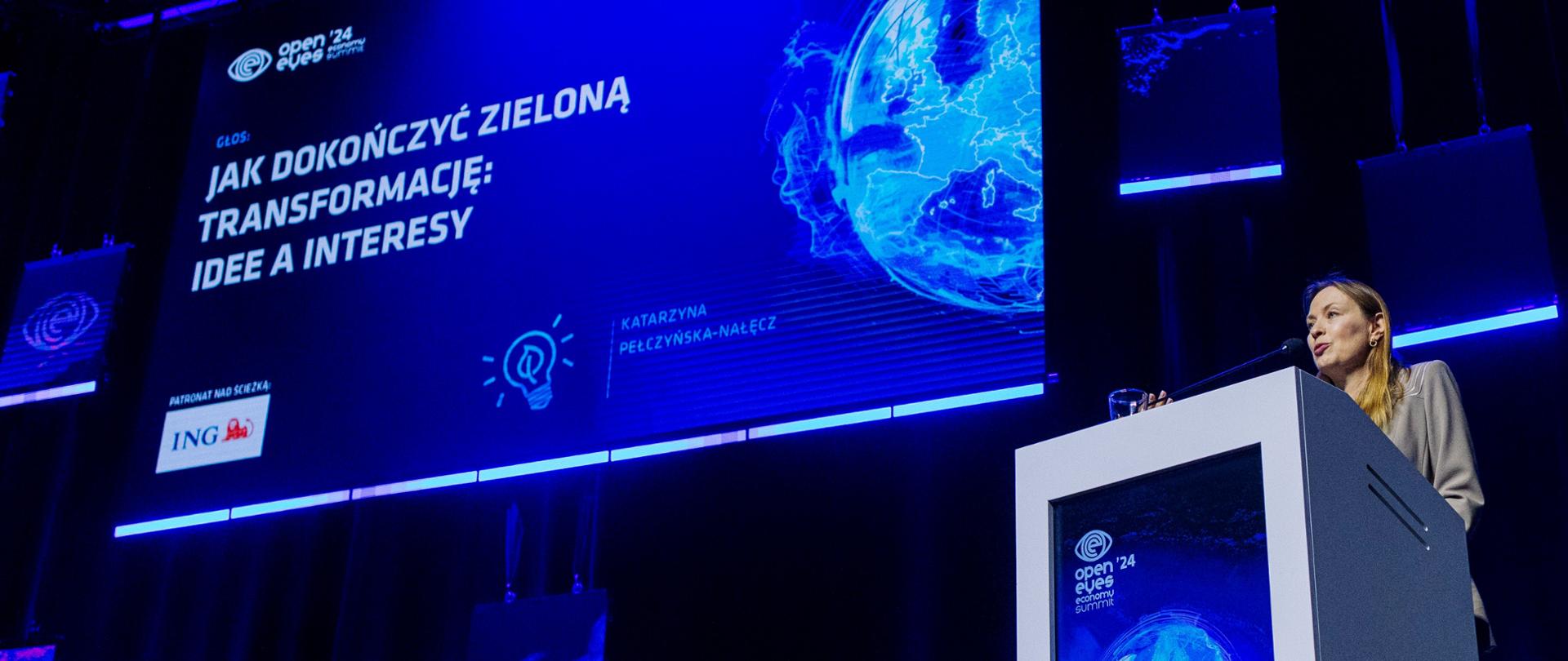 Minister Katarzyna Pełczyńska-Nałęcz stoi na scenie z prawej strony przy pulpicie.