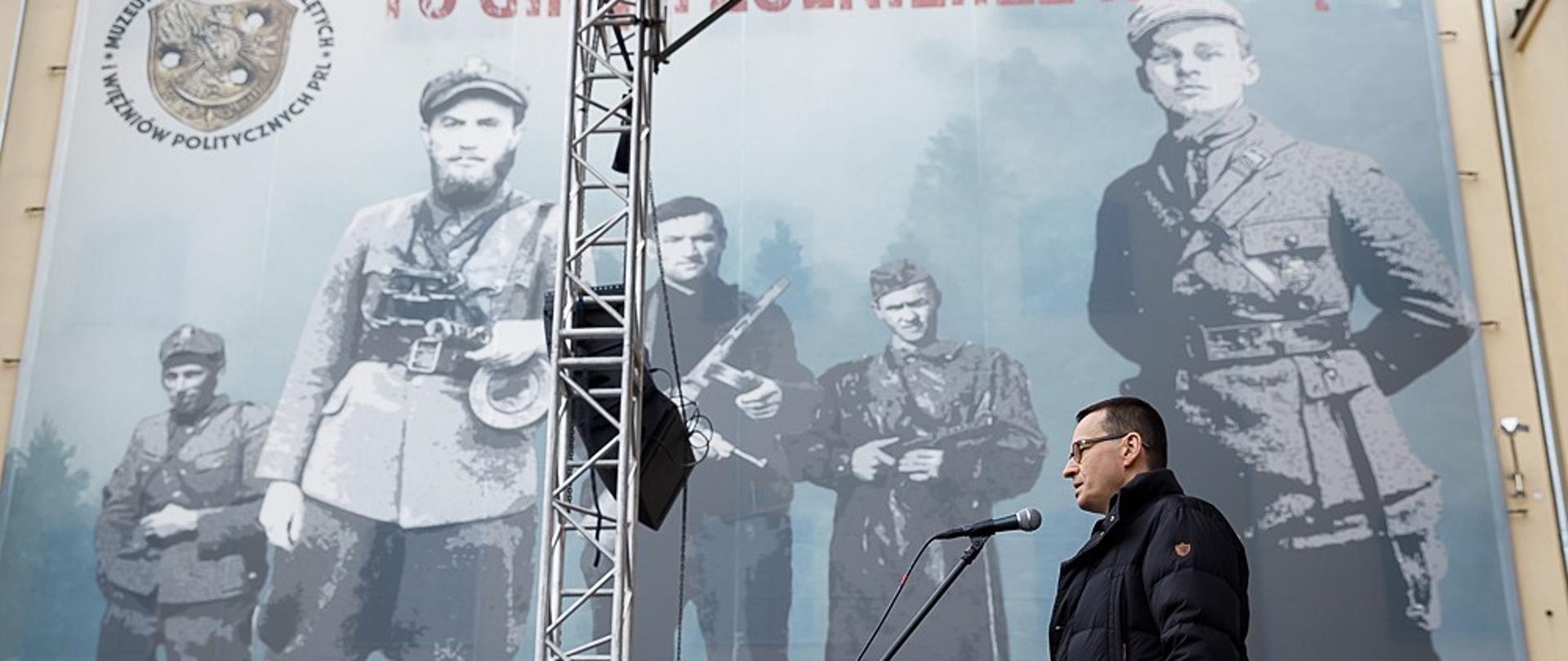 Premier na tle banneru muzeum.