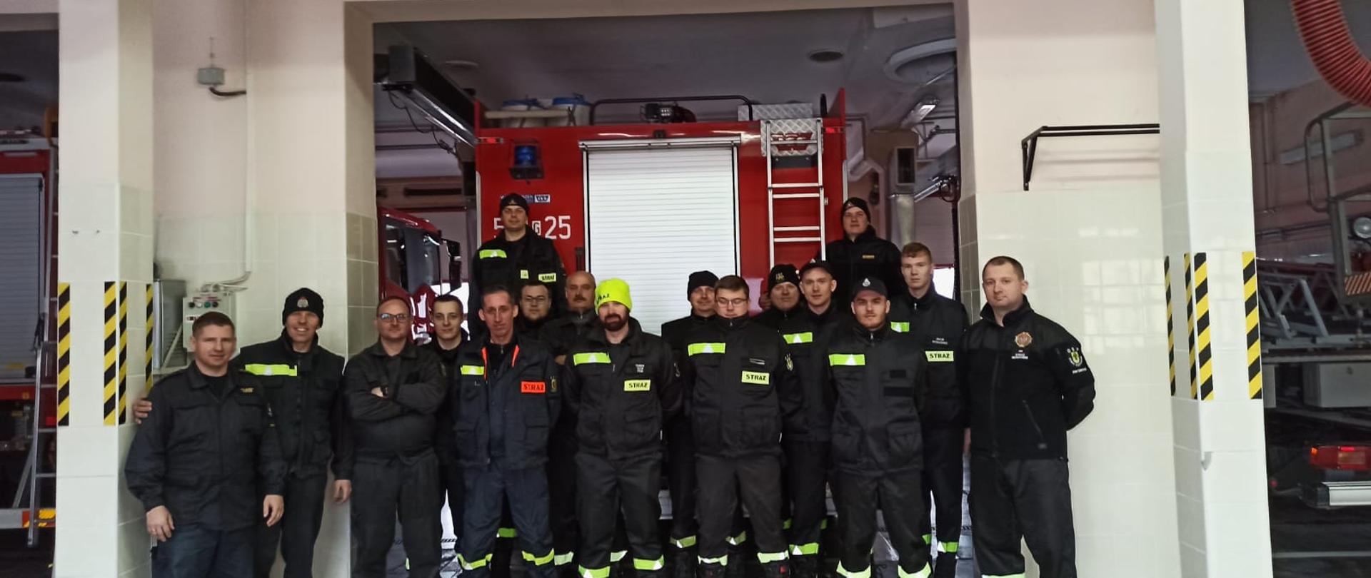 Na zdjęciu stoją druhowie i strażacy ubrani w mundury koszarowe i czapki.