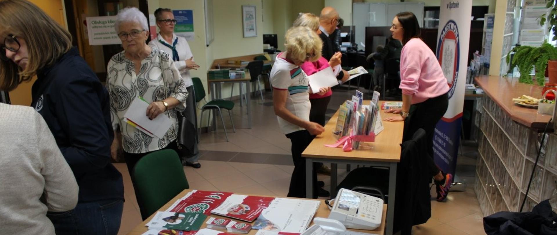 Osoby rozmawiające z przedstawicielkami Stacji Sanitarno-Epidemiologicznych i oglądające ulotki