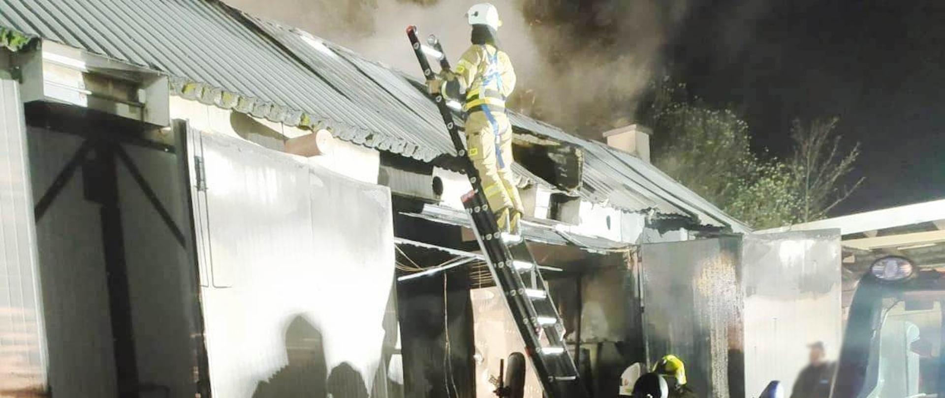 Strażak z drabiny gasi pożar