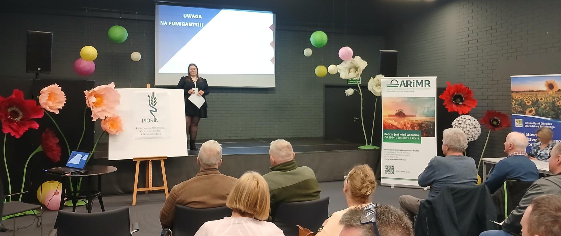 Uczestnicy spotkania siedzący na sali wykładowej z prelegentem.