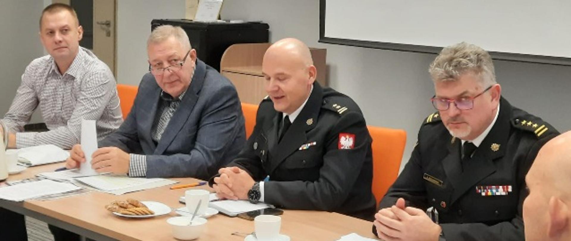 Zdjęcie obrazuje strażaków i osoby ubrane w ubranie cywilne