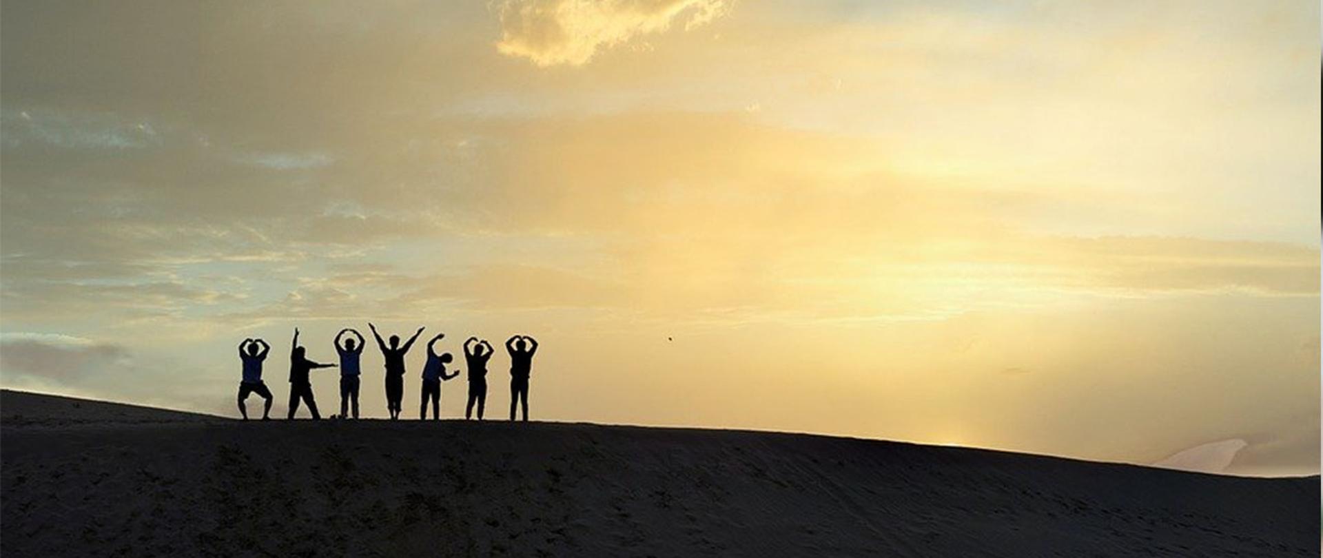 Na zdjęciu: grupa ludzi na tle zachodzącego słońca