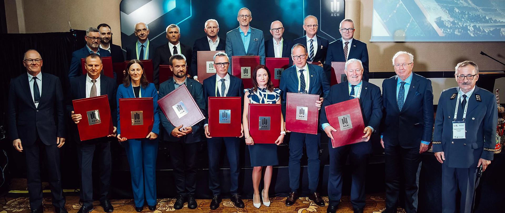 Grupa osób ustawiona w dwóch rzędach, laureaci tytułu „Przyjaciel Górnictwa Odkrywkowego", trzyma w rękach okolicznościowy dyplomy