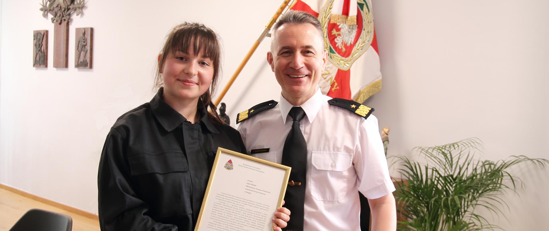 Nastoletnia ratowniczka z wizytą u komendanta głównego PSP – na zdjęciu komendant główny PSP nadbryg. Andrzej Bartkowiak oraz Zofia Sikora, członkini Młodzieżowej Drużyny Pożarniczej w Śmiglu z listem gratulacyjnym.