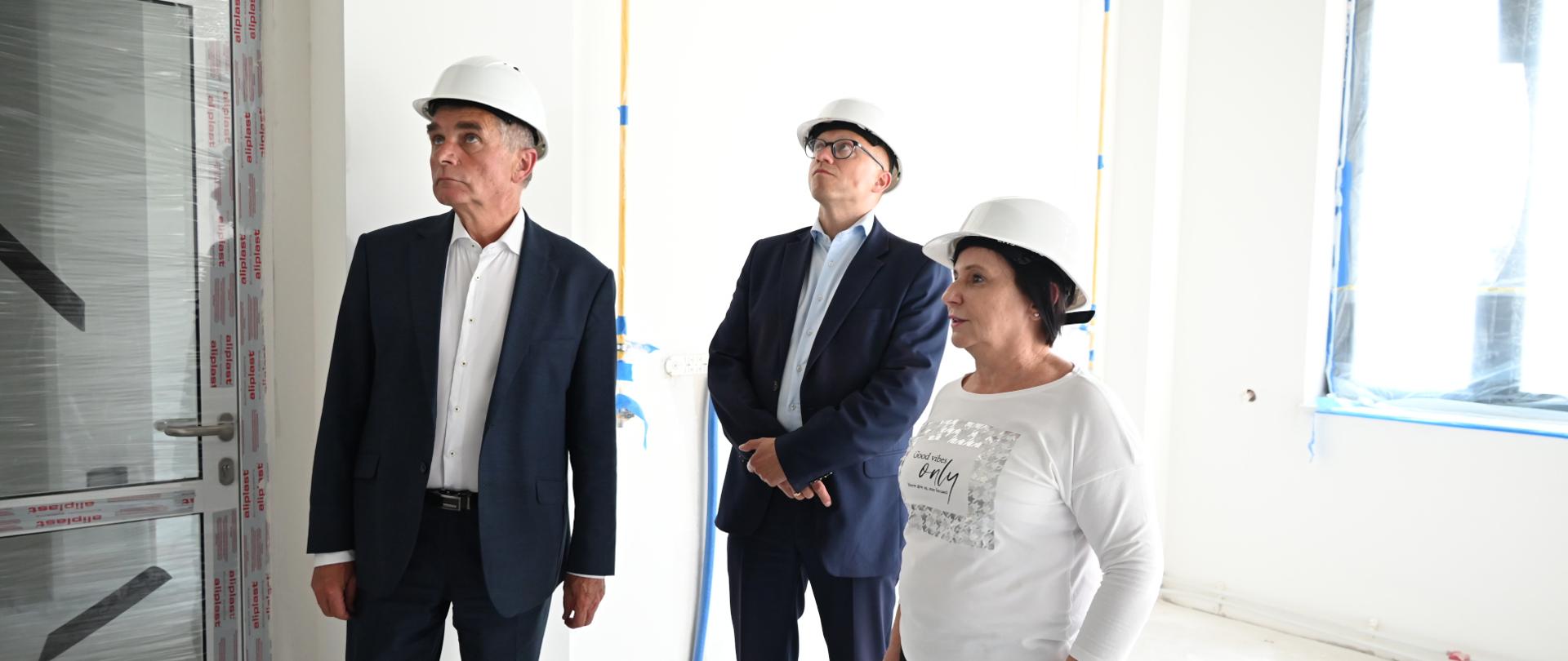 osoby wizytujące patrzące w górę w pomieszczeniu przyszłego laboratorium