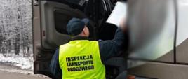 Umundurowany funkcjonariusz mazowieckiej Inspekcji Transportu Drogowego stoi obok otwartych drzwi kabiny ciężarówki i pobiera wymagane dokumenty do kontroli od kierowcy.