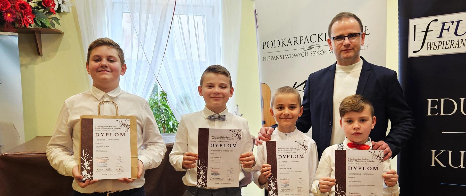 Zdjęcie nauczyciela oraz uczniów prezentujących dyplomy