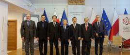 Zdjęcie przedstawiające grupę mężczyzn przedstawicieli strony polskiej i japońskiej stojących na tle flag polskich i Unii Europejskiej 