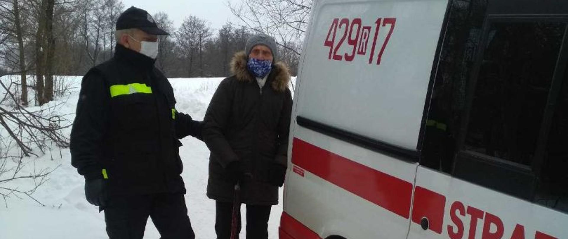 transport osoby do punktów szczepień, biały samochód z oznaczeniami osp, strażak w ubraniu z oznaczeniami osp i starsza osoba wsiadająca do samochodu