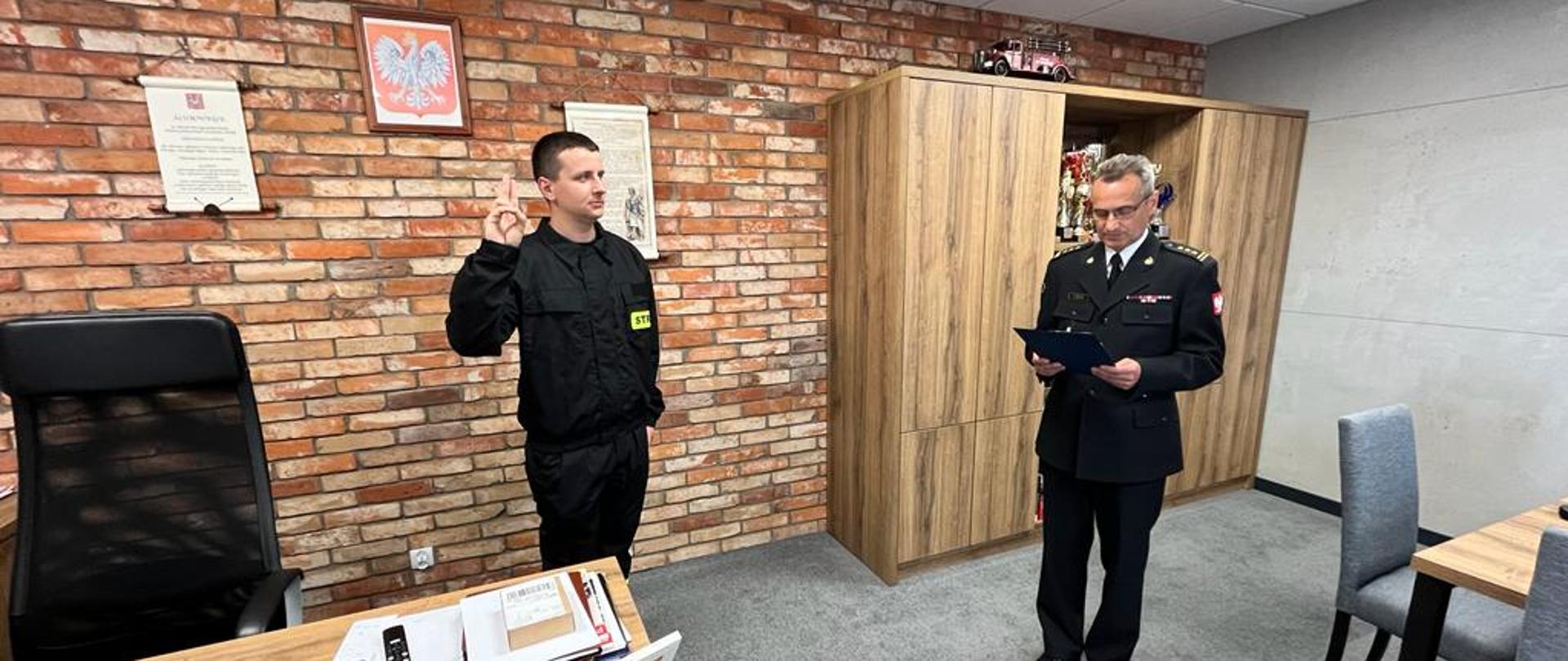 Na zdjęciu po prawej stronie Zastępca Komendanta Powiatowego Państwowej Straży Pożarnej w Świeciu starszy brygadier Andrzej Rafalski odczytujący akt ślubowania strażaka Daniela Pajdosz