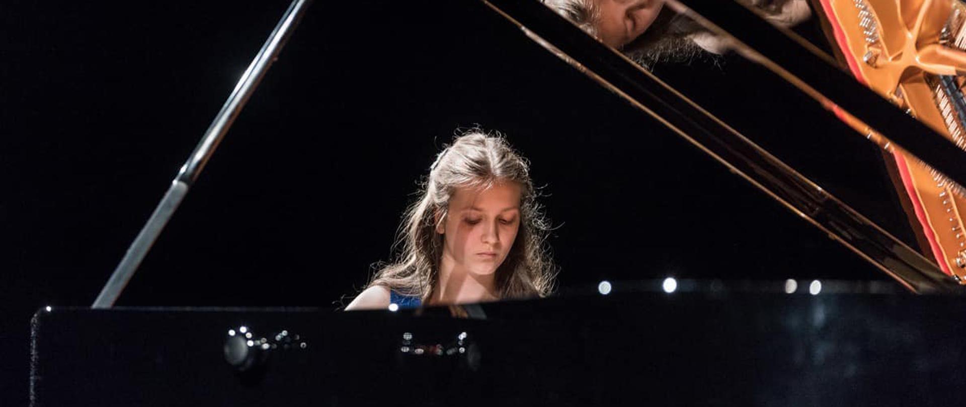 Pianistka siedzi przy fortepianie.