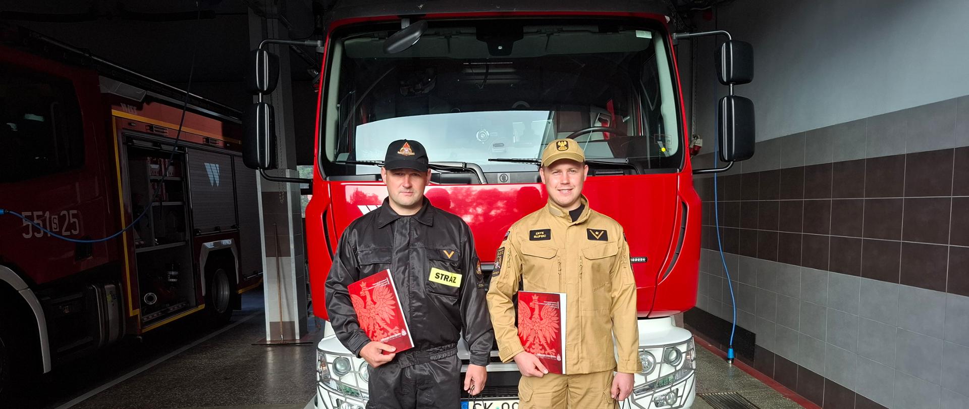 Wyróżnieni za swoją postawę strażacy JRG stojący na tle pojazdów i garażu
