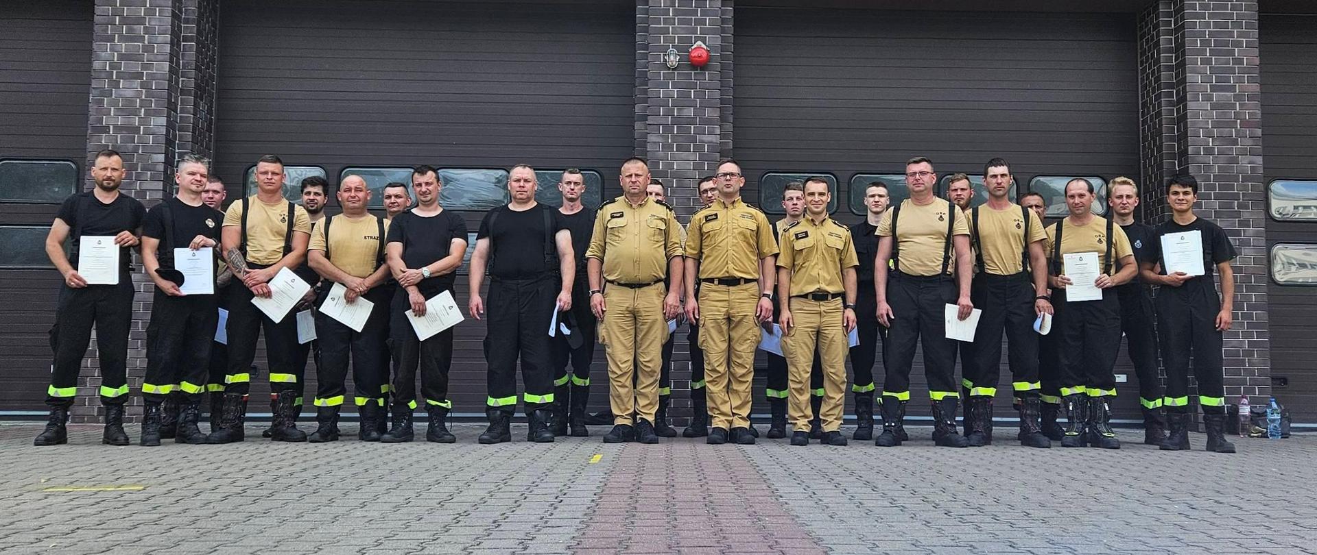 Egzaminatorzy i kursanci stoją przed budynkiem komendy.