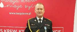 Strażak mł. ogn. Dariusz Chrostowski w mundurze z odznaczeniem Honorowy Dawca Krwi - Zasłużony dla Zdrowia Narodu