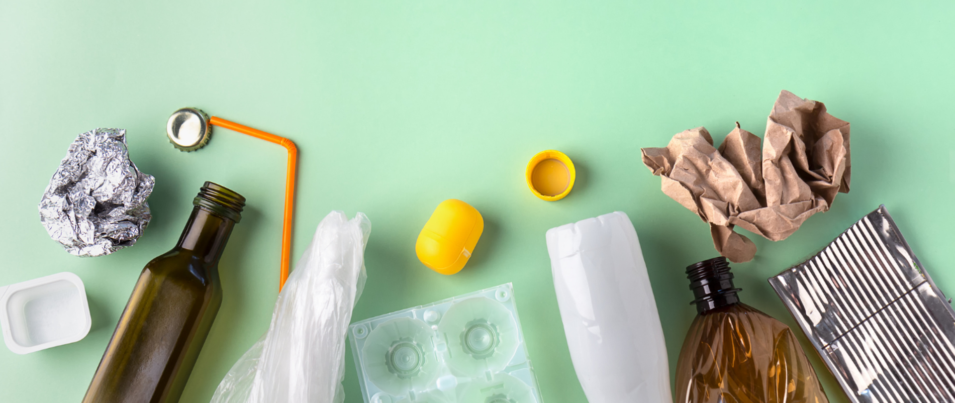 na zdjęciu widnieją materiały do recyklingu np. szklane butelki, plastikowe torebki, papierowe opakowania. 