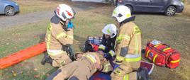 Zdjęcie przedstawia strażaków OSP podczas udzielania pierwszej pomocy osobie poszkodowanej. 