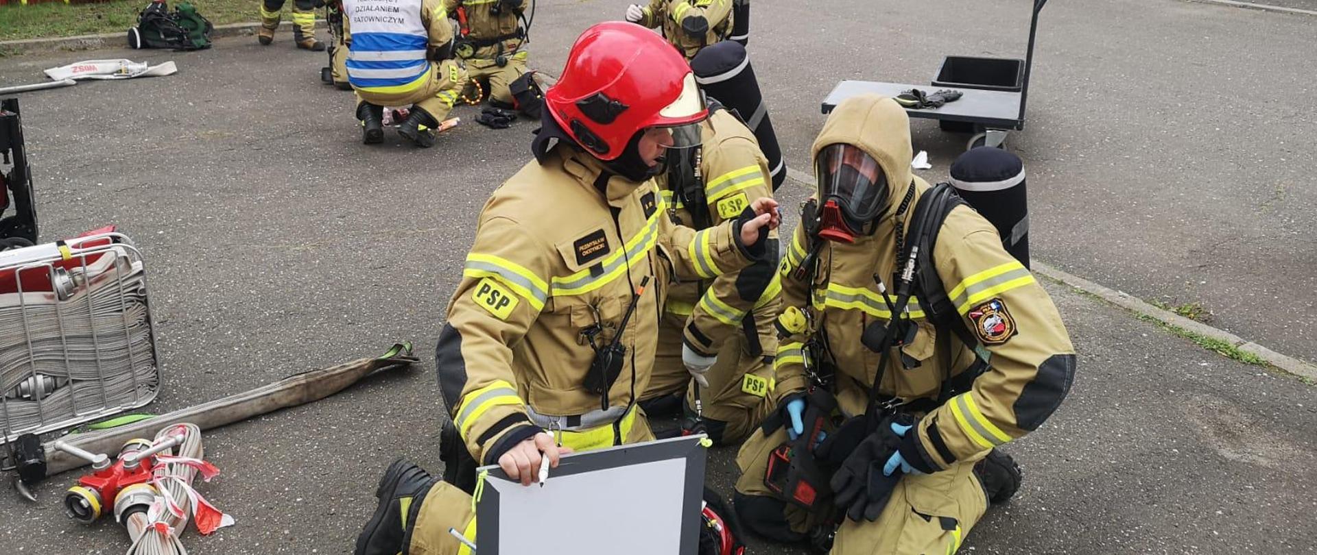 Na zdjęciu widnieją strażacy podczas ćwiczeń w symulatorze gaszenia pożarów wewnętrznych