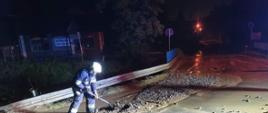 Usuwanie błota przez strażaków z jezdni