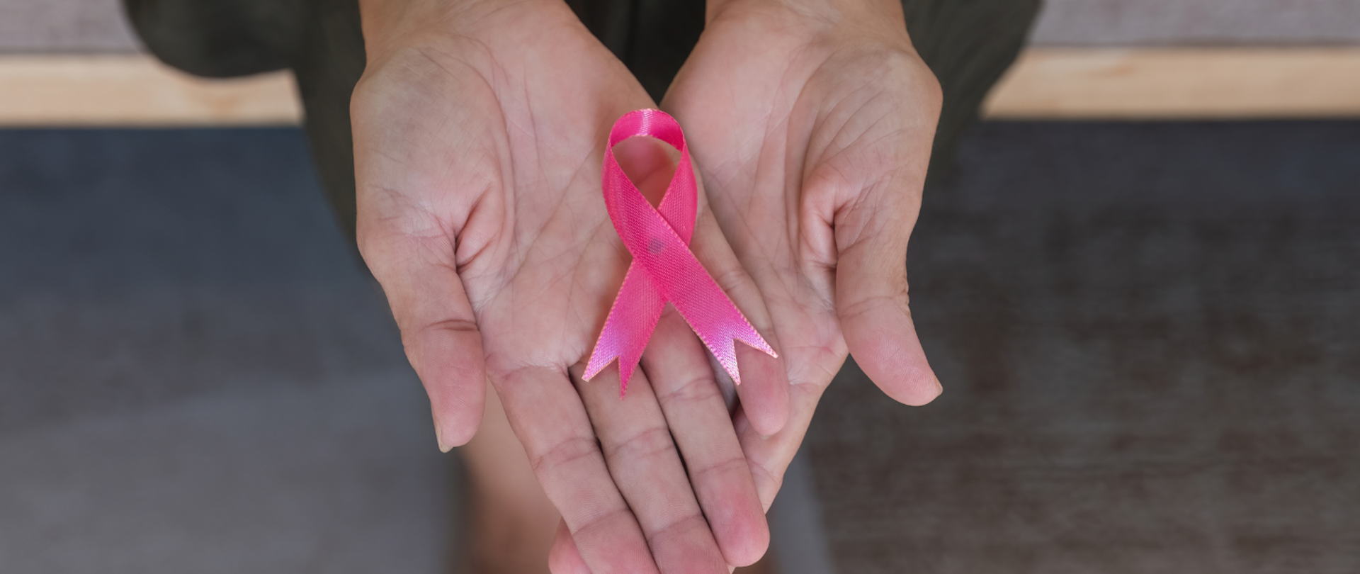 Różowa wstążka na kobiecych dłoniach.