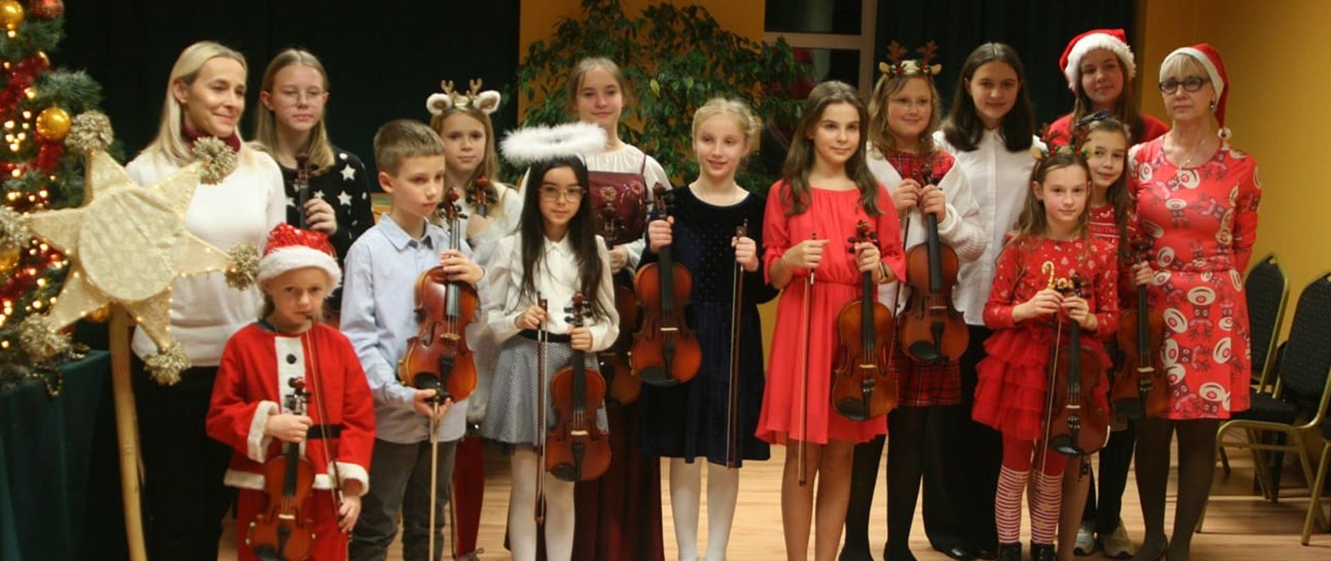 Grupowe zdjęcie uczniów klasy skrzypiec. Uczniowie trzymają w dłoniach skrzypce i smyczki