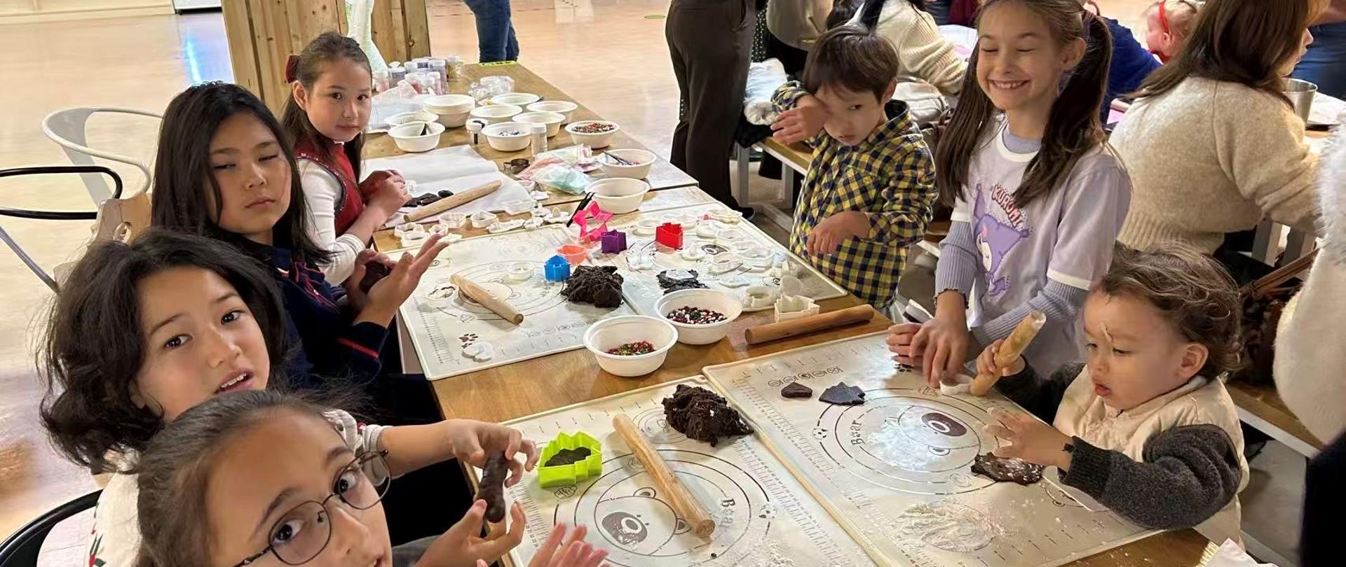 Dzieci przy stole robią pierniki z ciasta