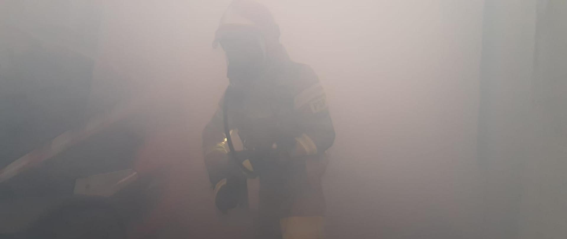 Strażacy pracujący w zadymieniu w hali magazynowej