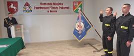 Nowo przyjęci strażacy ślubują komendantami być ofiarnym i mężnym w ratowaniu życia ludzkiego i wszelkiego mienia. Z boku stoi sztandar. 