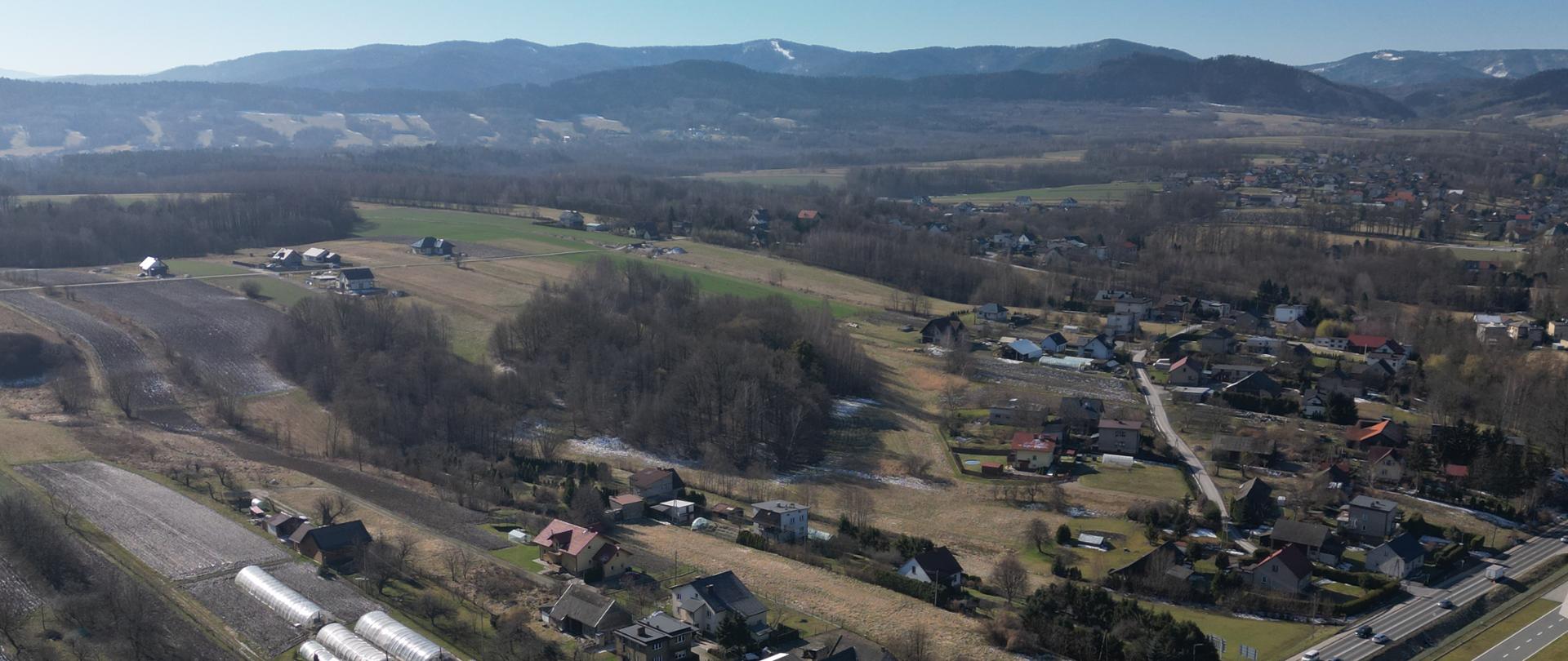 Węzeł Chocznia, teren przyszłej BDI, w dolnej części zdjęcia zabudowania, w środkowej głównie pola, w oddali Beskidy. Zdjęcie lotnicze