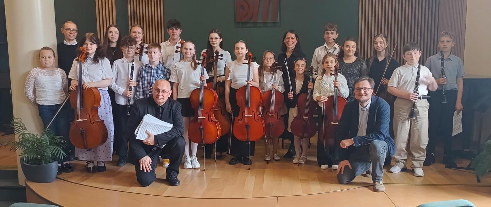 Na zdjęciu widać uśmiechniętych uczniów klasy klarnetu saksofonu skrzypiec wiolonczeli oraz nauczycieli.