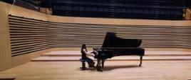 Nastolatka gra na fortepianie w sali koncertowej.